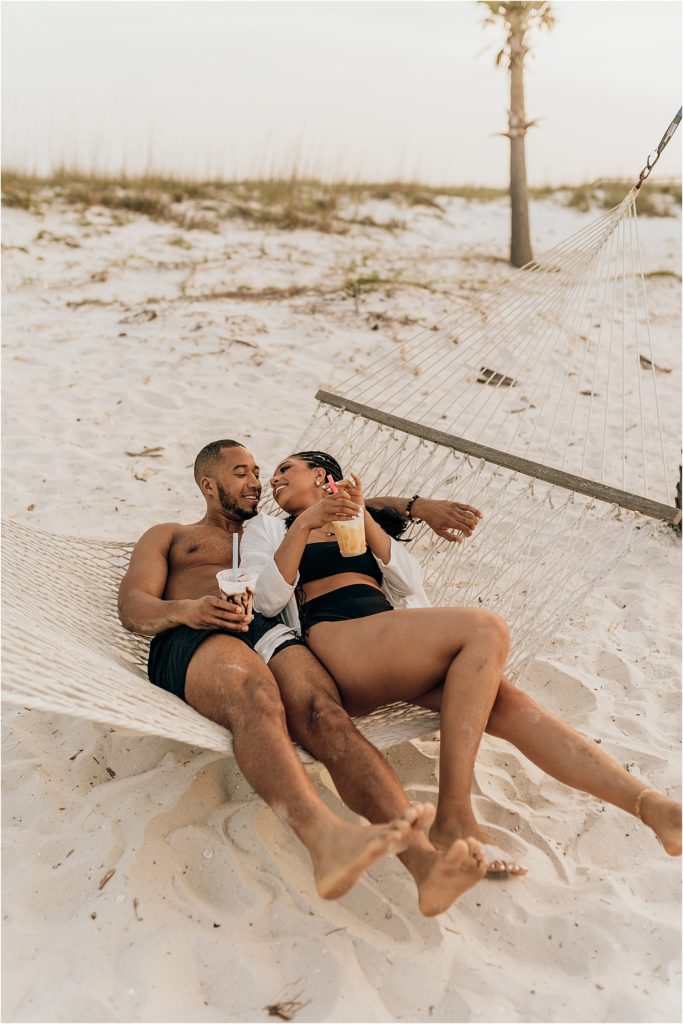black couple drinking in hammock on beach