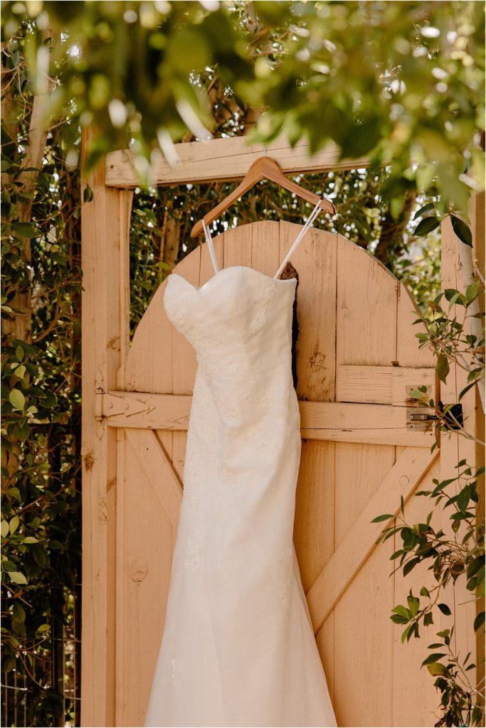 Wedding dress hanging on gate at backyard palm springs wedding venue