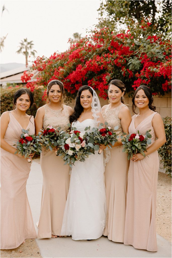 wedding party posing in front of flowers at backyard palm springs wedding venue