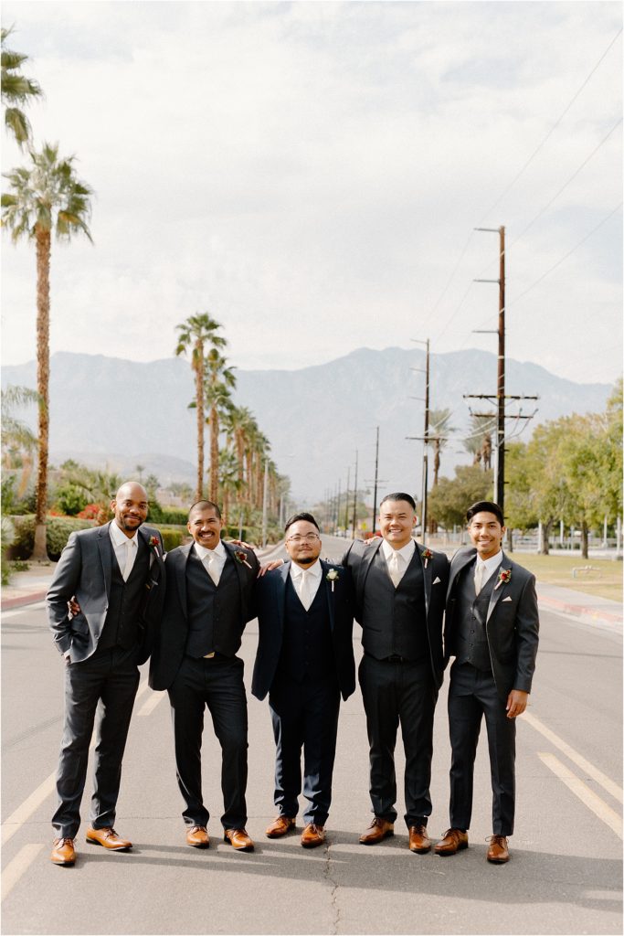 wedding party posing in front of mountains and palm trees at backyard palm springs wedding venue