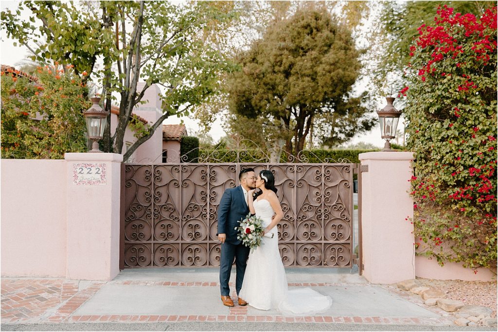 wedding couple kissing in front of pink wall at backyard palm springs wedding venue