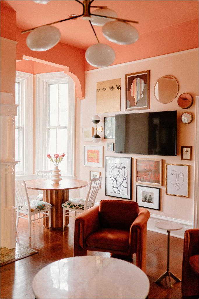 Upstairs living area with pink walls, gallery wall art, and velvet furniture